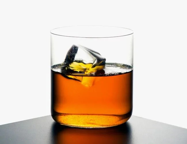 Glass of whisky with ice front white background.