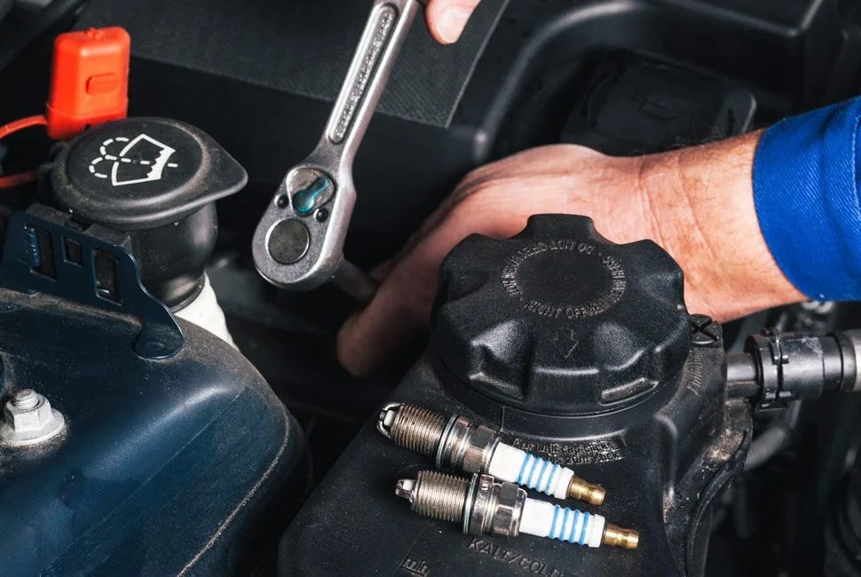 Mechanic is unscrewing the ignition plugs of a modern car