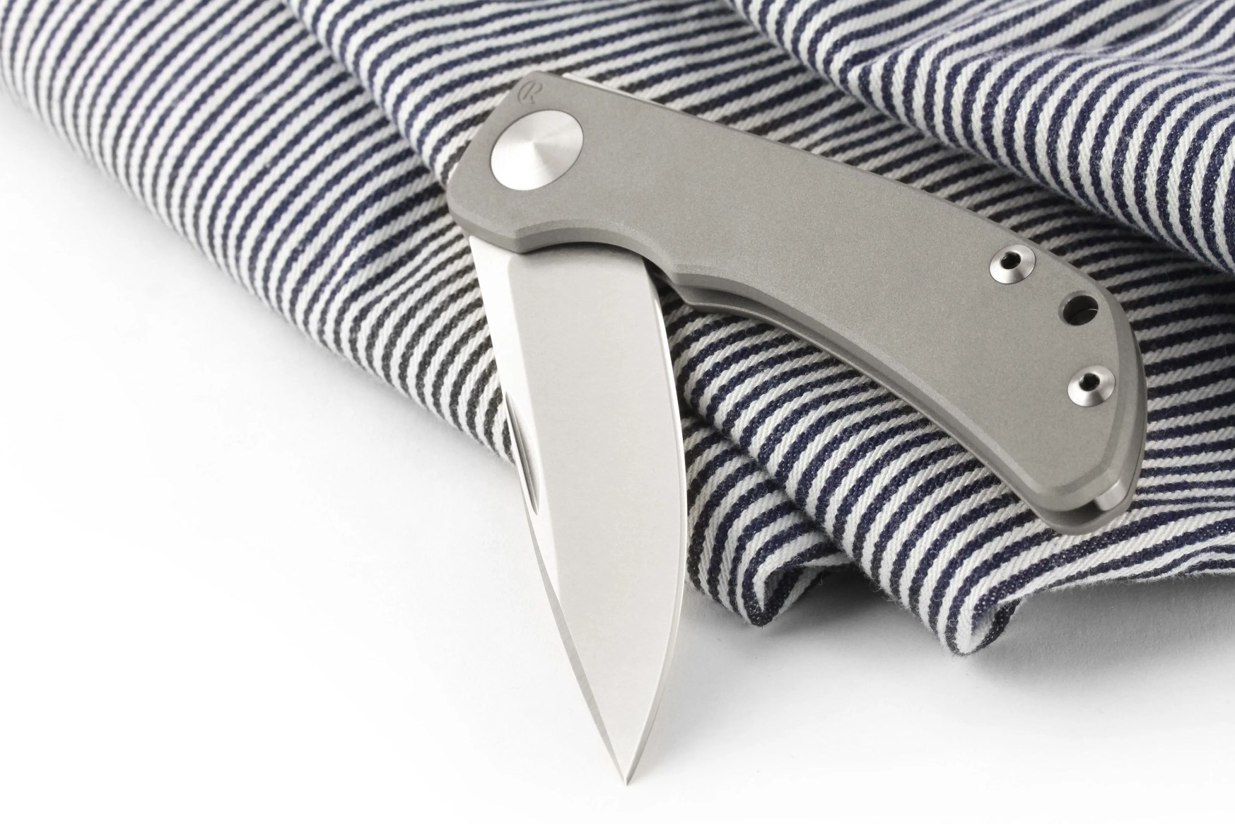 pocketknife laying on top of a blue and white striped towel
