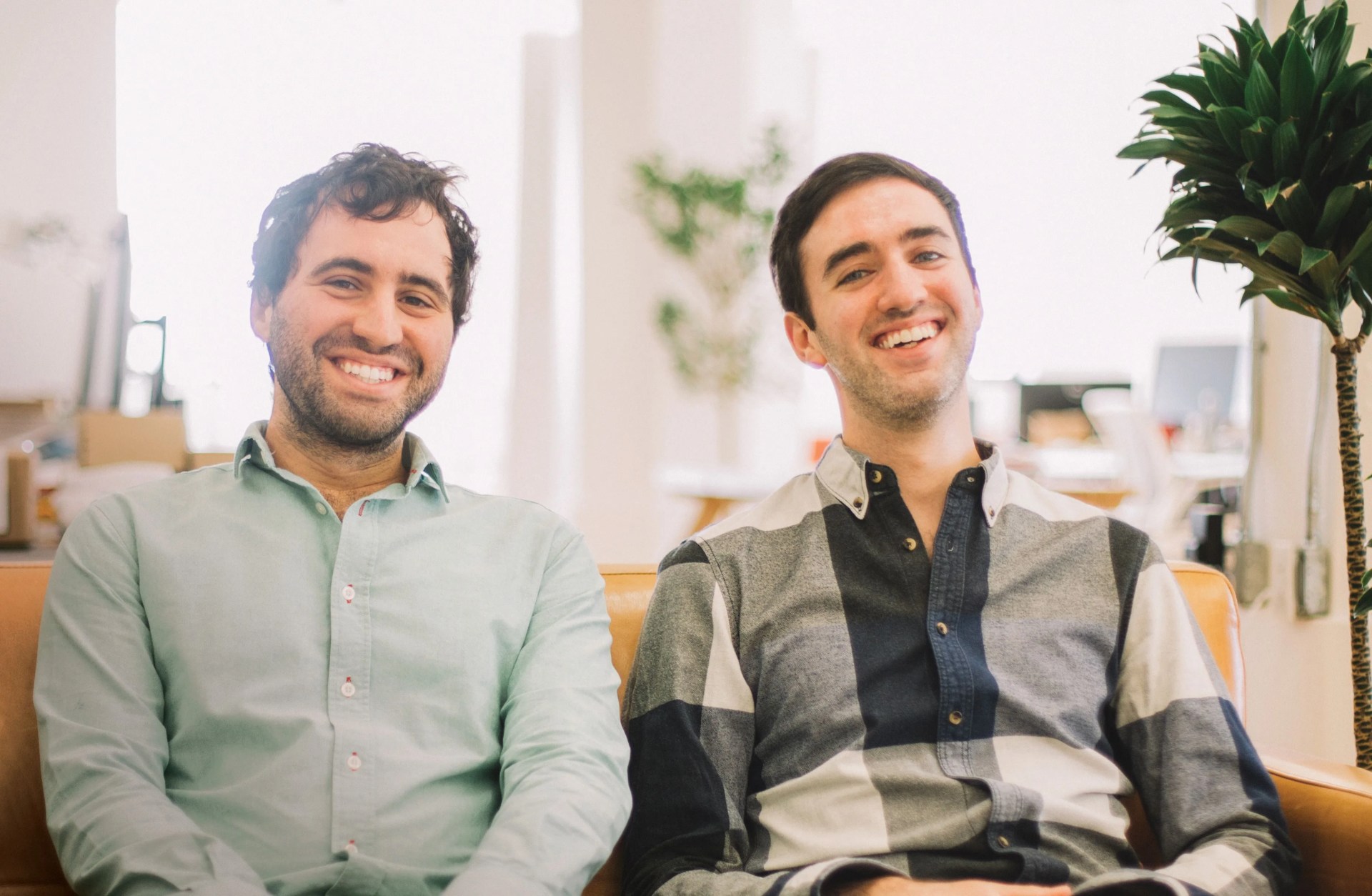 two men sitting on a sofa and smiling