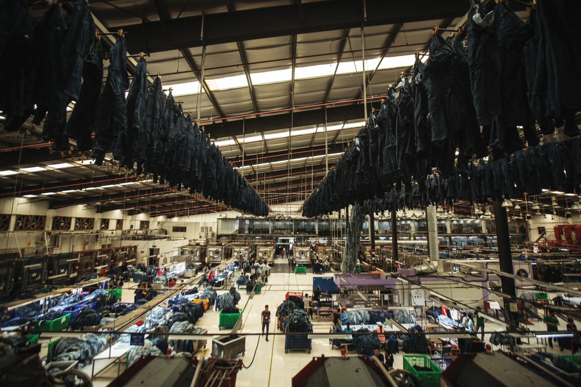 large warehouse with workers and piles of denim on tables