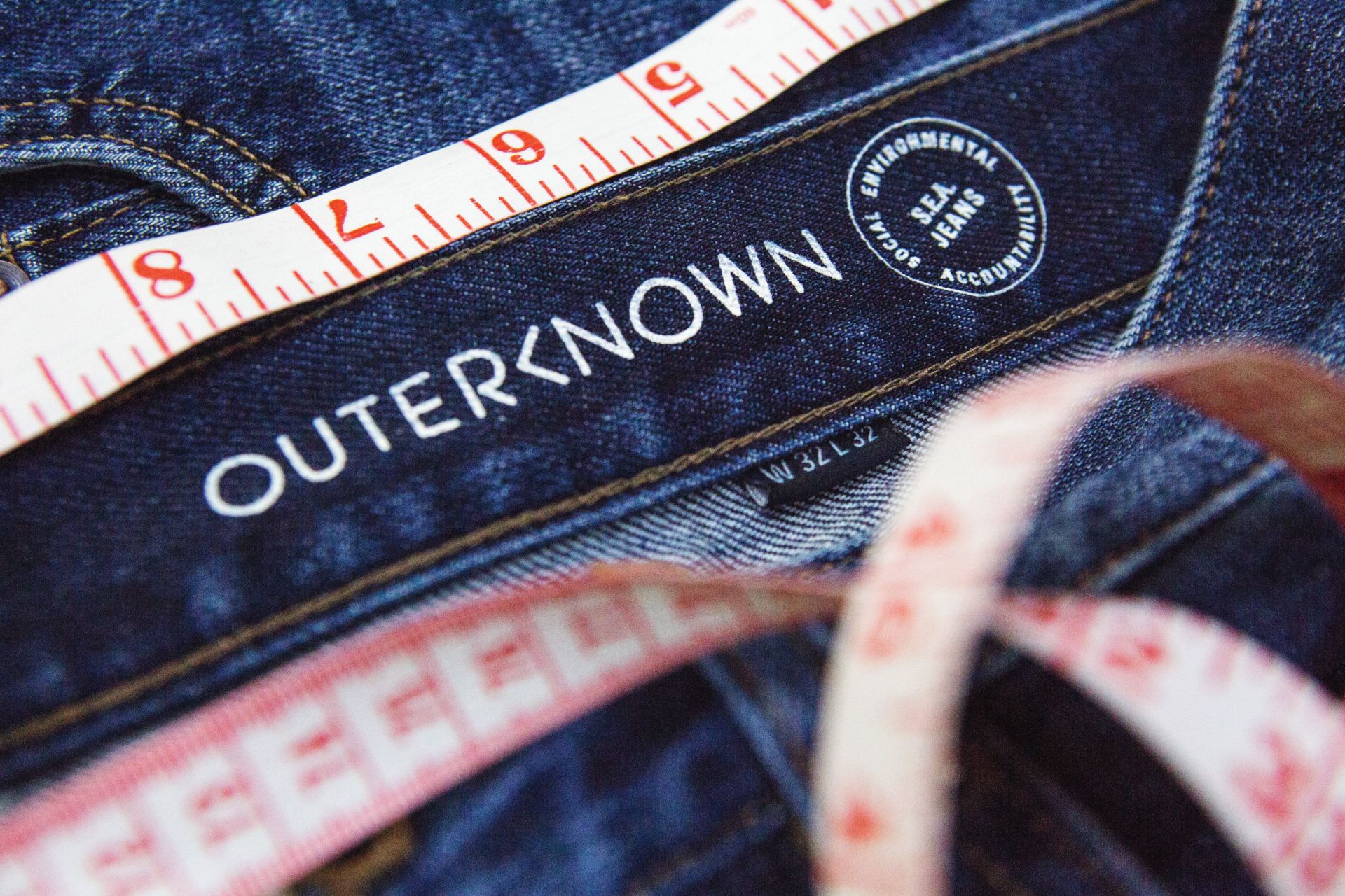 interior of a waistband of outerknown jeans with a tape measure laying on top
