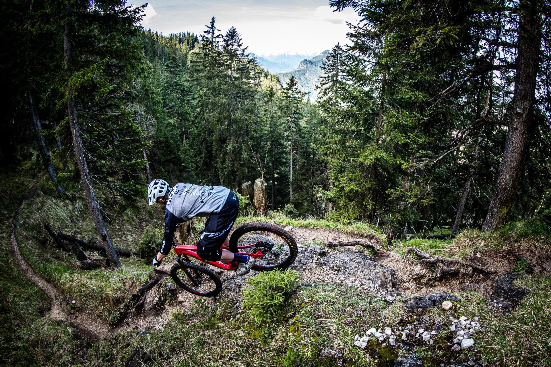 man riding a red mountain bike down a rocky hill