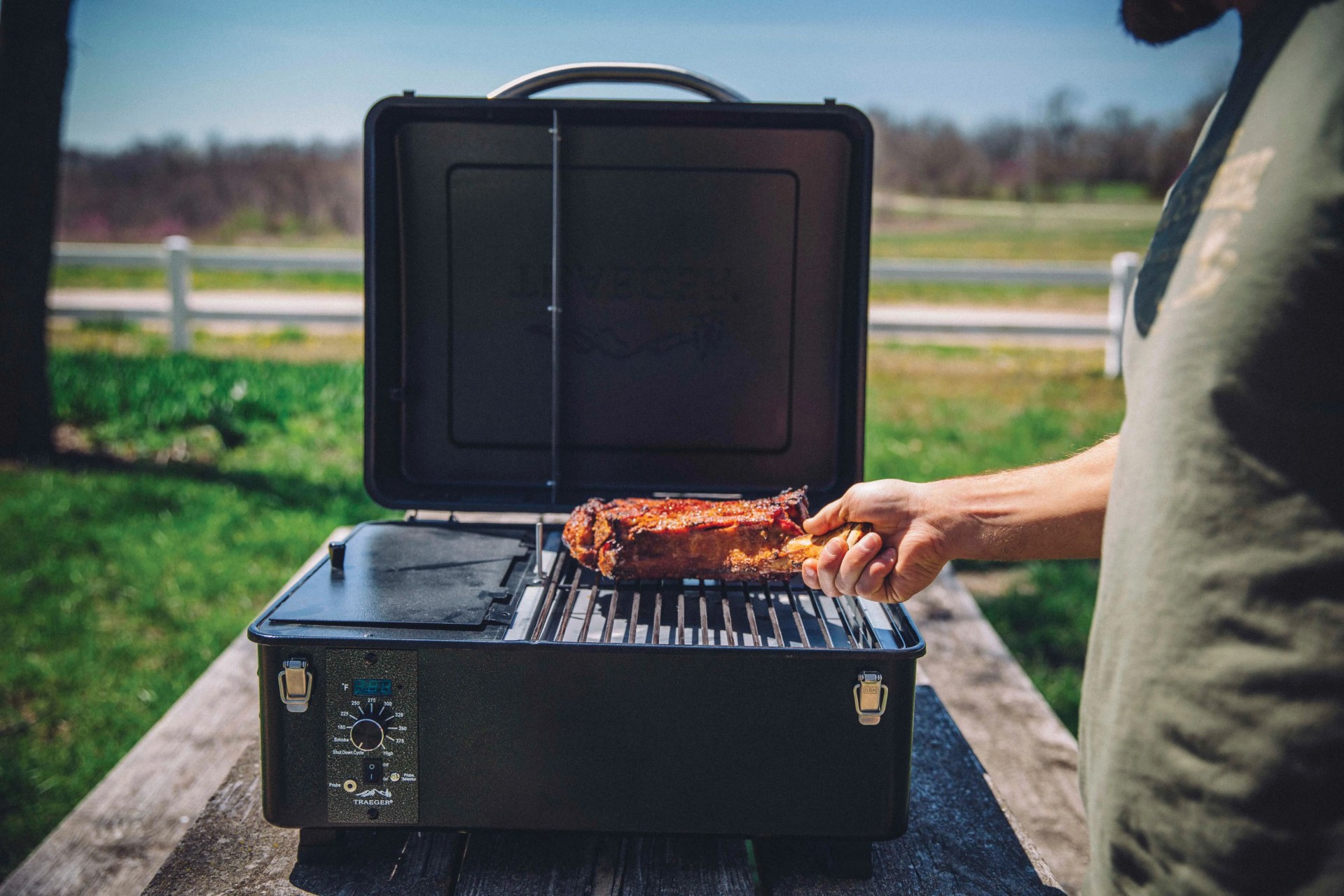 man grilling meat on a trager grill