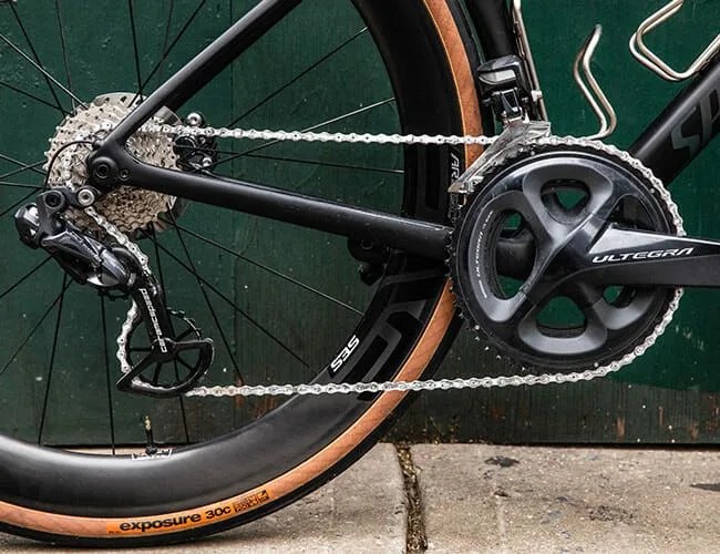 a close up of the gears, chain, derailleur, rear wheel and pedals of a black bicycle