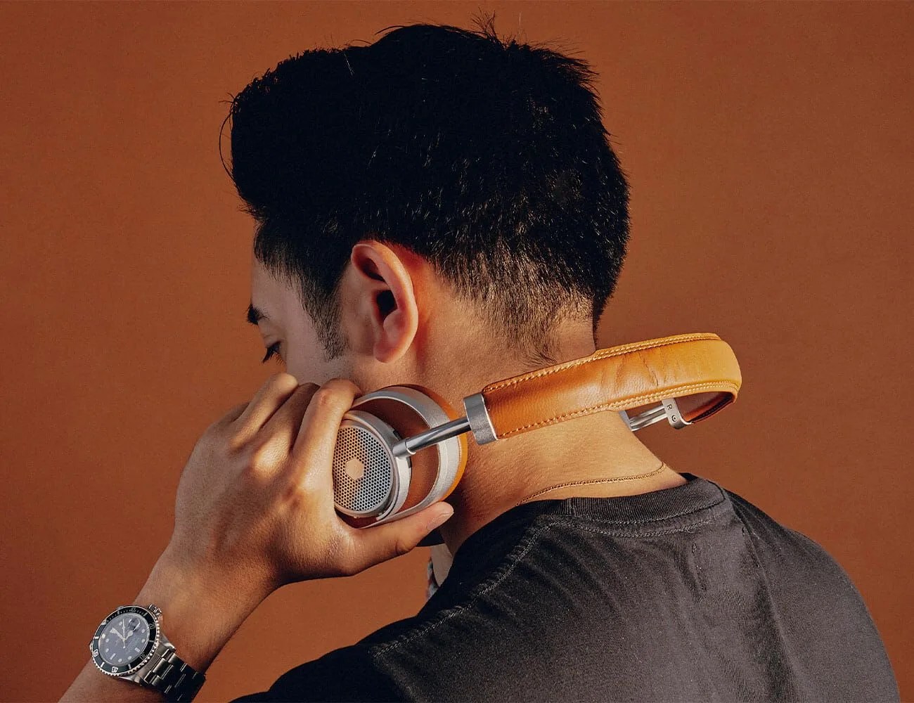 man holding pair of headphones around his neck