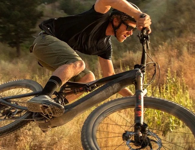 a man making a wide turn on a black electric mountain bike