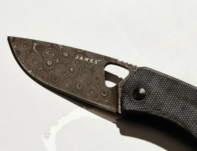 a damascus steel pocket knife blade on a white background