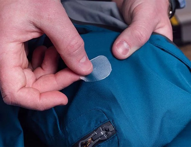 a person patching a hole in a jacket