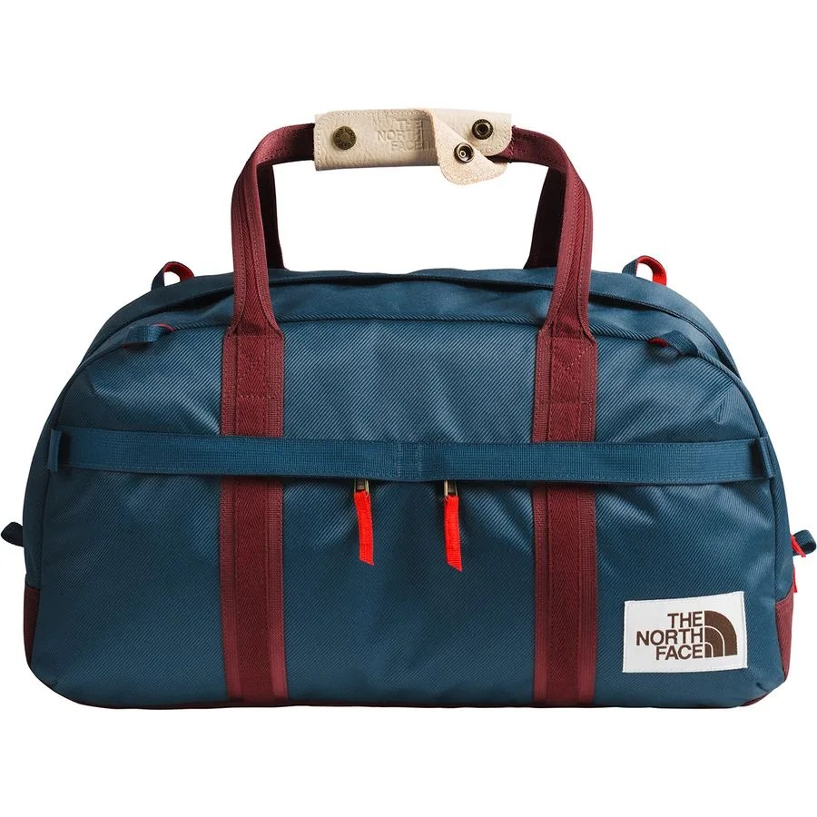 A blue, teal and red duffel back on a white background.