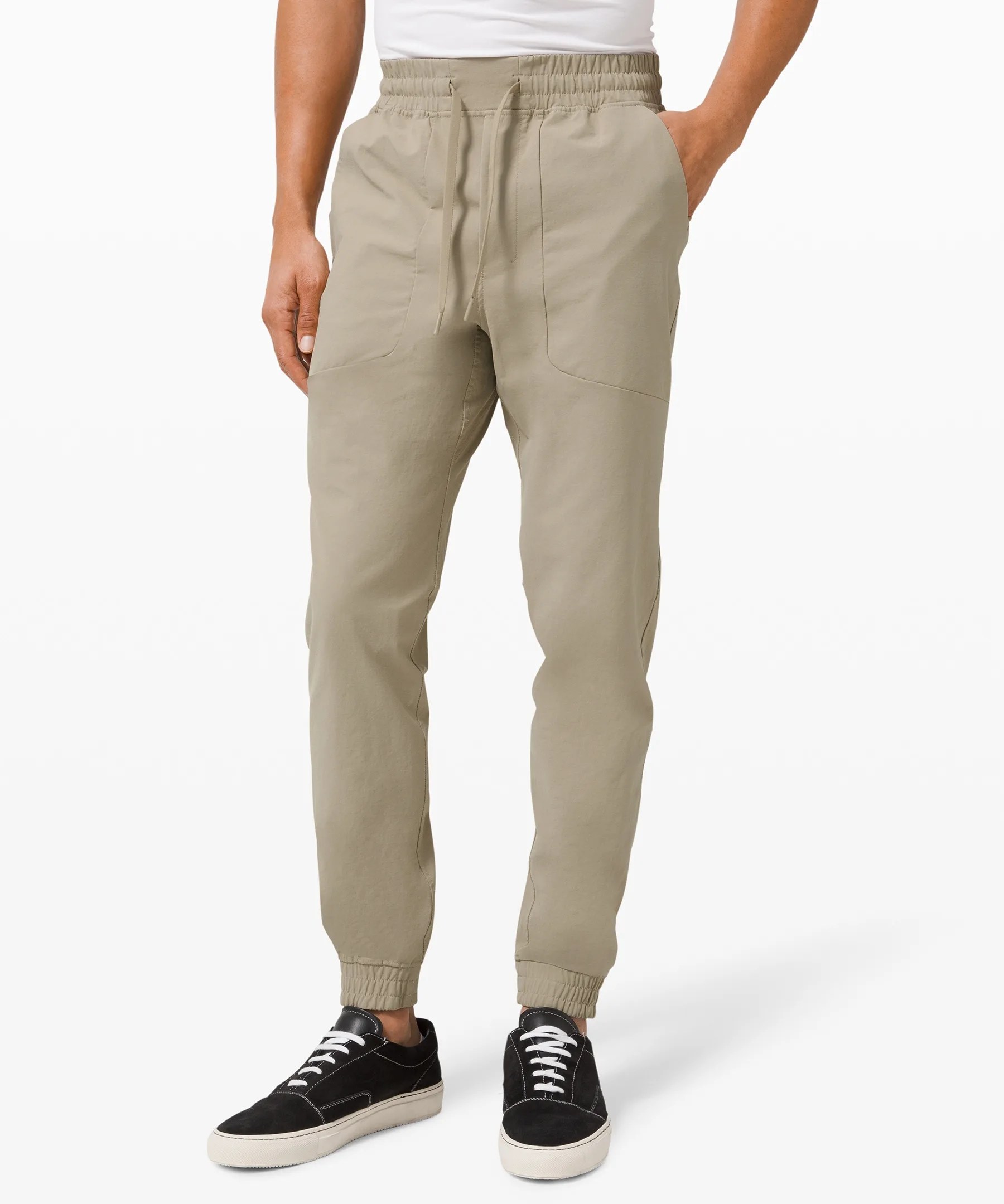 Tan colored jogger pants on a model on a white background.