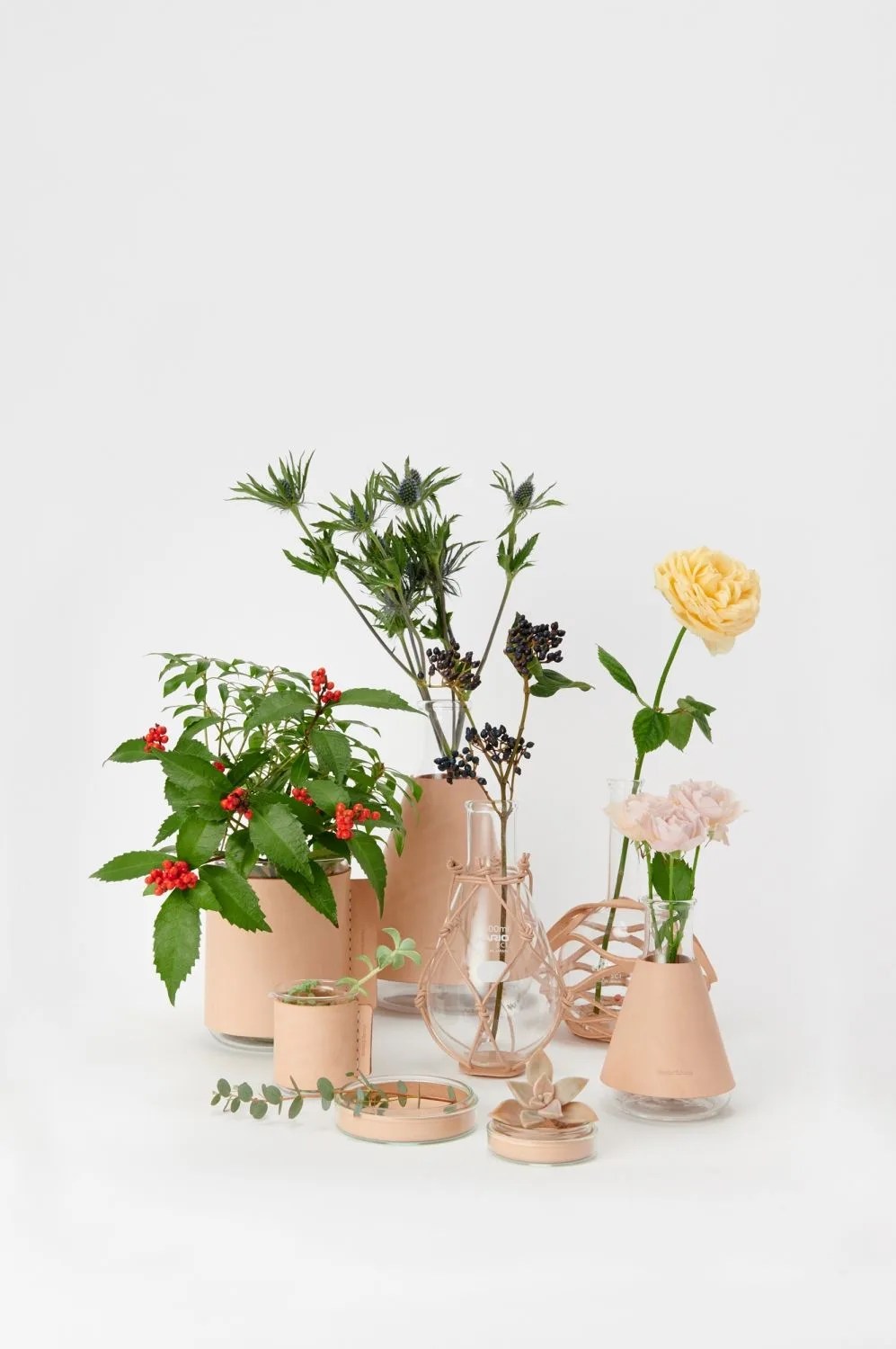 collection of petri dishes and beakers wrapped in leather and filled with flowers