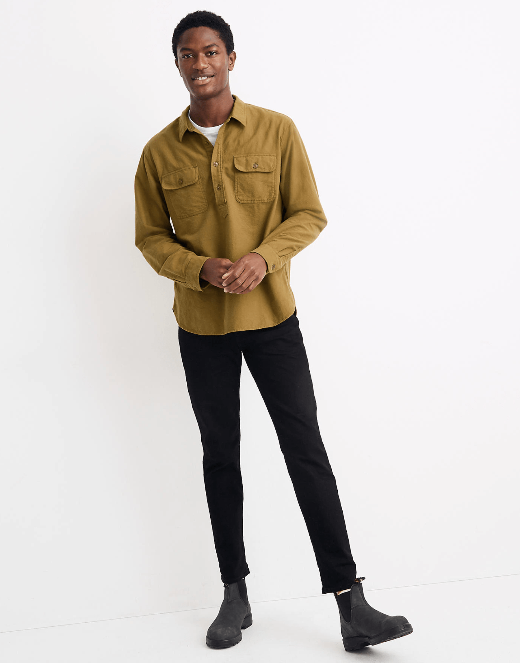 An olive moleskine pullover shirt on a model with a white undershirt and black pants on a white background.