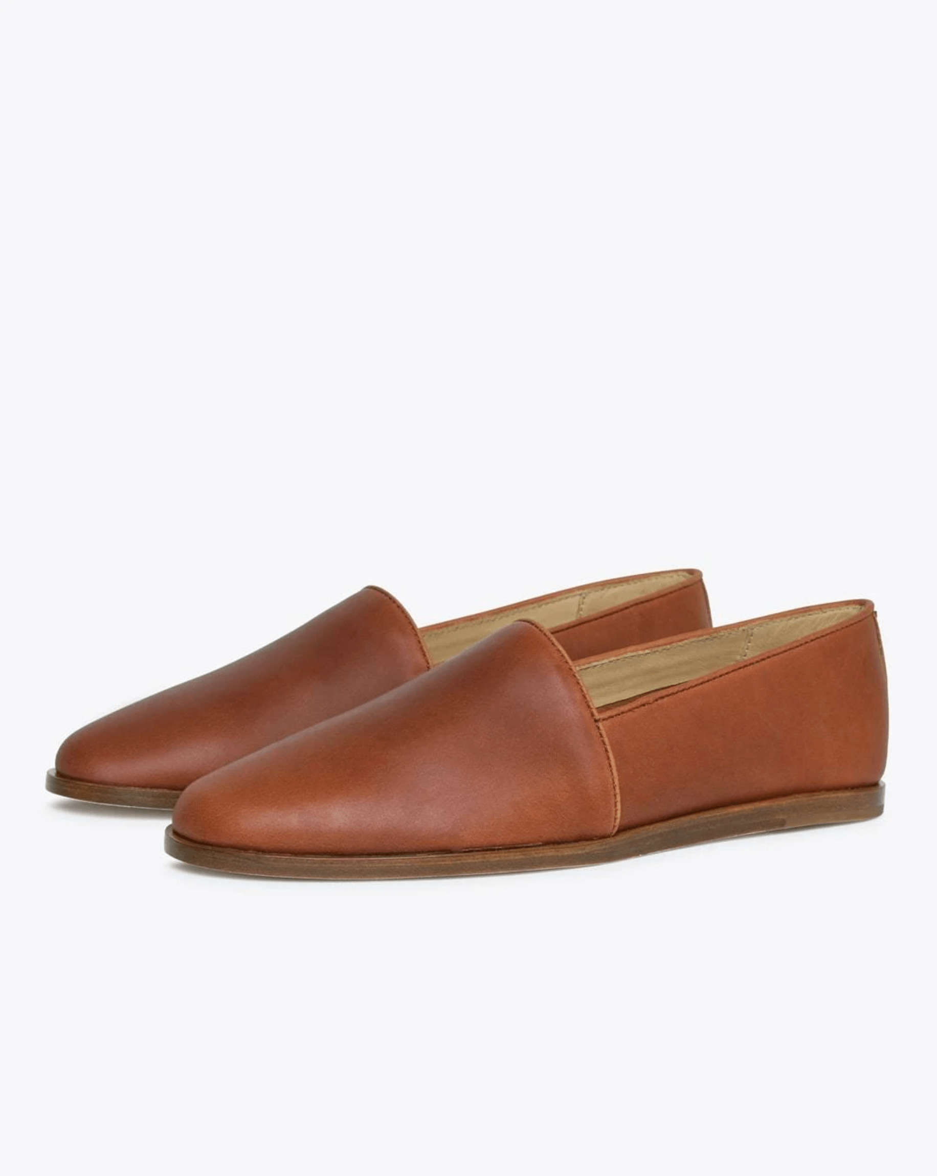 Brown leather pair of slip on shoes on a white background.