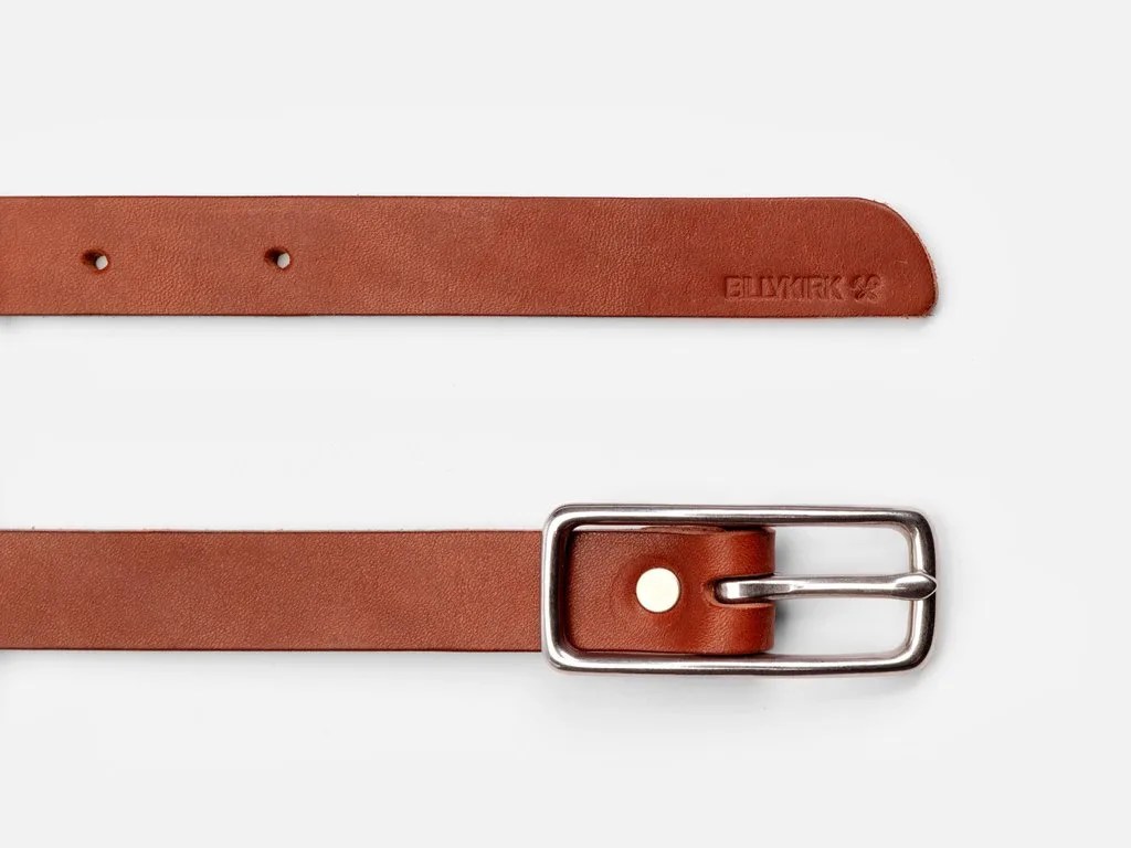 A brown leather belt with a nickel colored buckle on a white background.