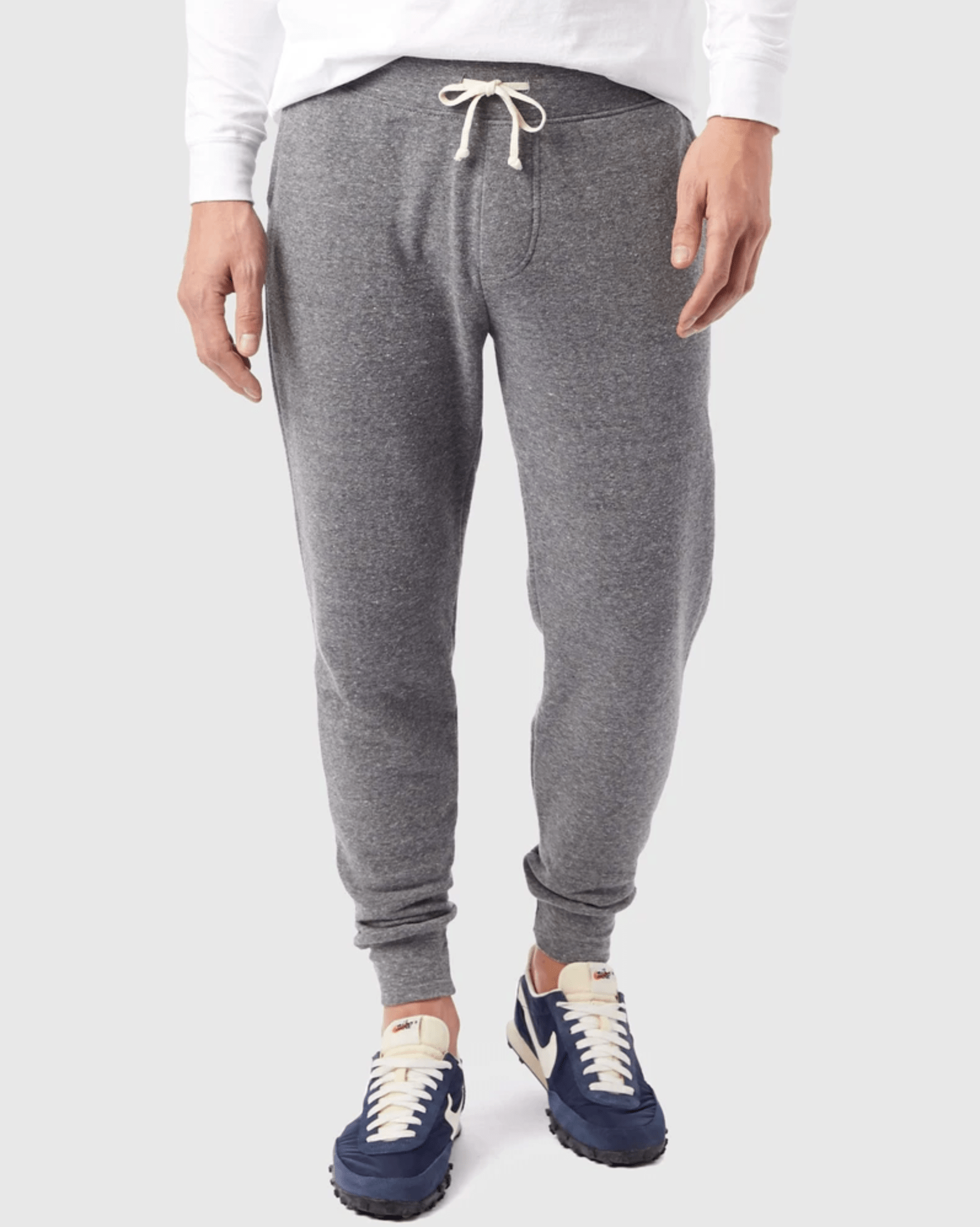 Gray jogger sweatpants on a model on a gray background.