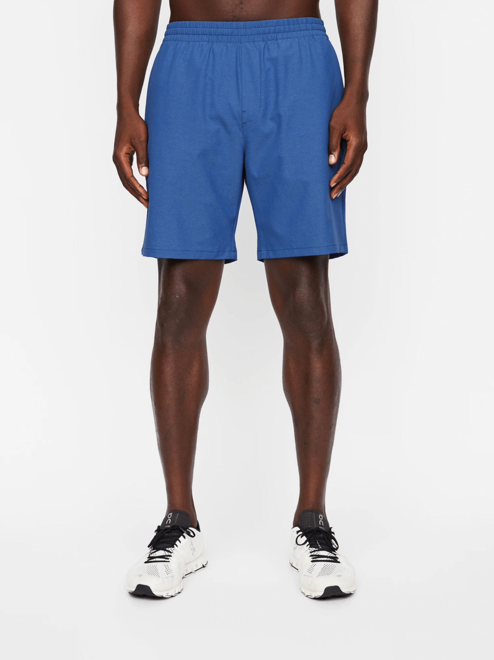 Blue athletic shorts on a model on a gray background.
