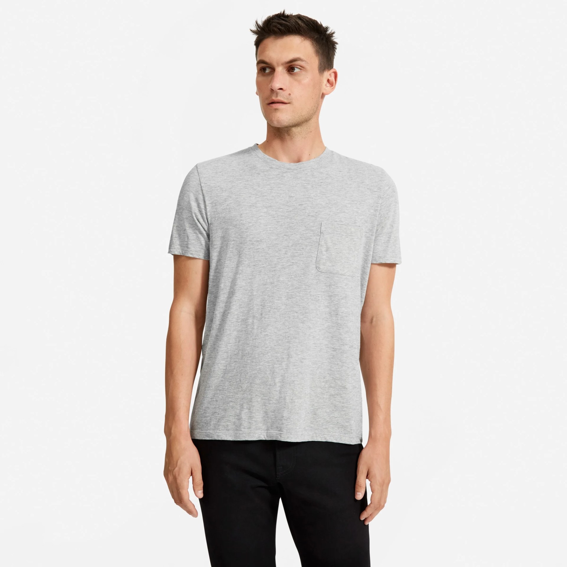 A model wearing a gray pocket t-shirt with black pants on a gray background.