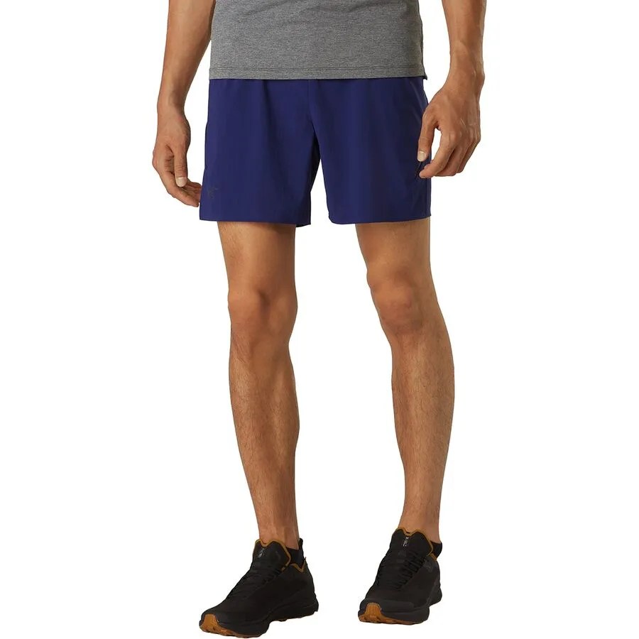 the lower half of a man wearing blue shorts and black sneakers