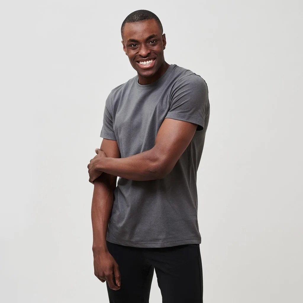 A model with a gray t-shirt and black pants on a gray background.