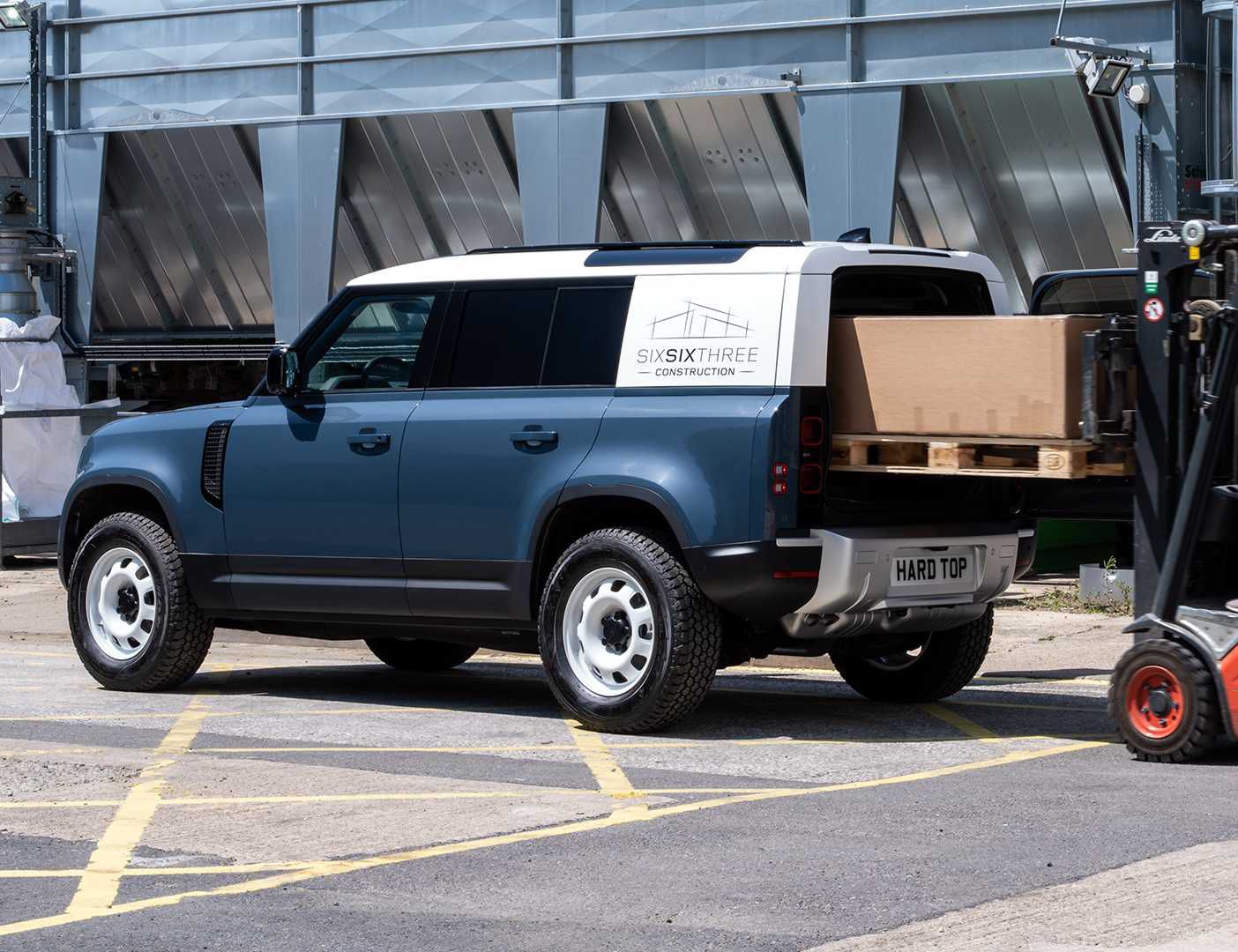 cargo being loaded into the back of a land rover defender hard top