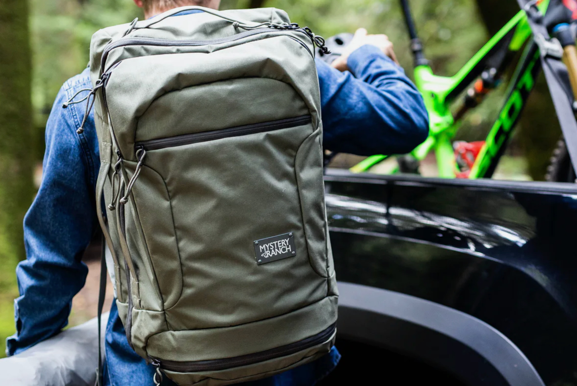 a model loading up a truck with a backpack, bike and tent bag