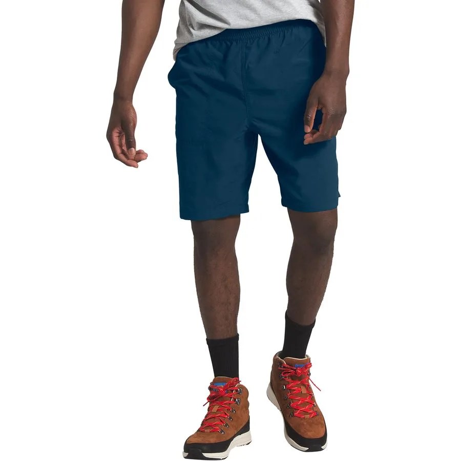A model wearing blue shorts, black socks and hiking boots on a gray background.