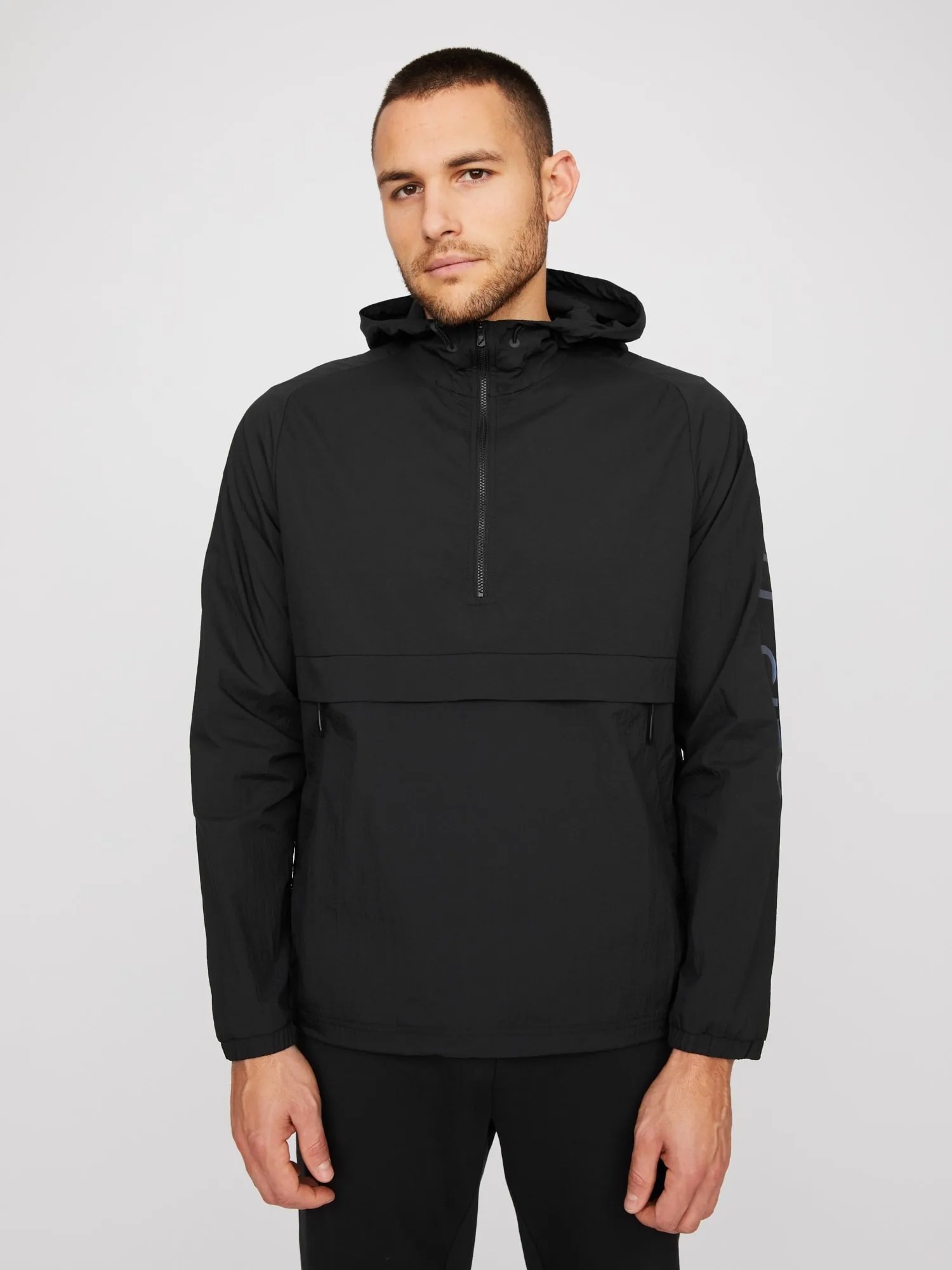 A model wearing a black anorak on a gray background.