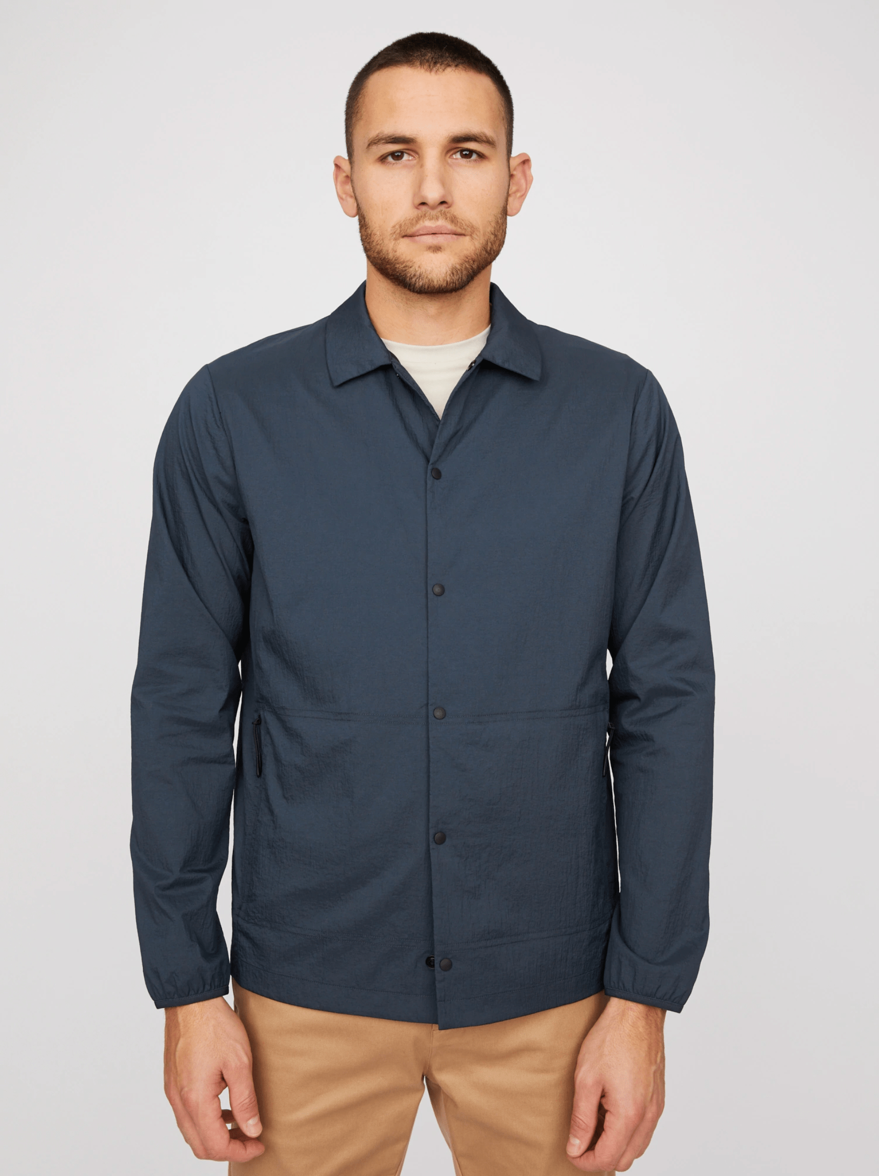 A model wearing a blue shirt jacket and khakis on a gray background.