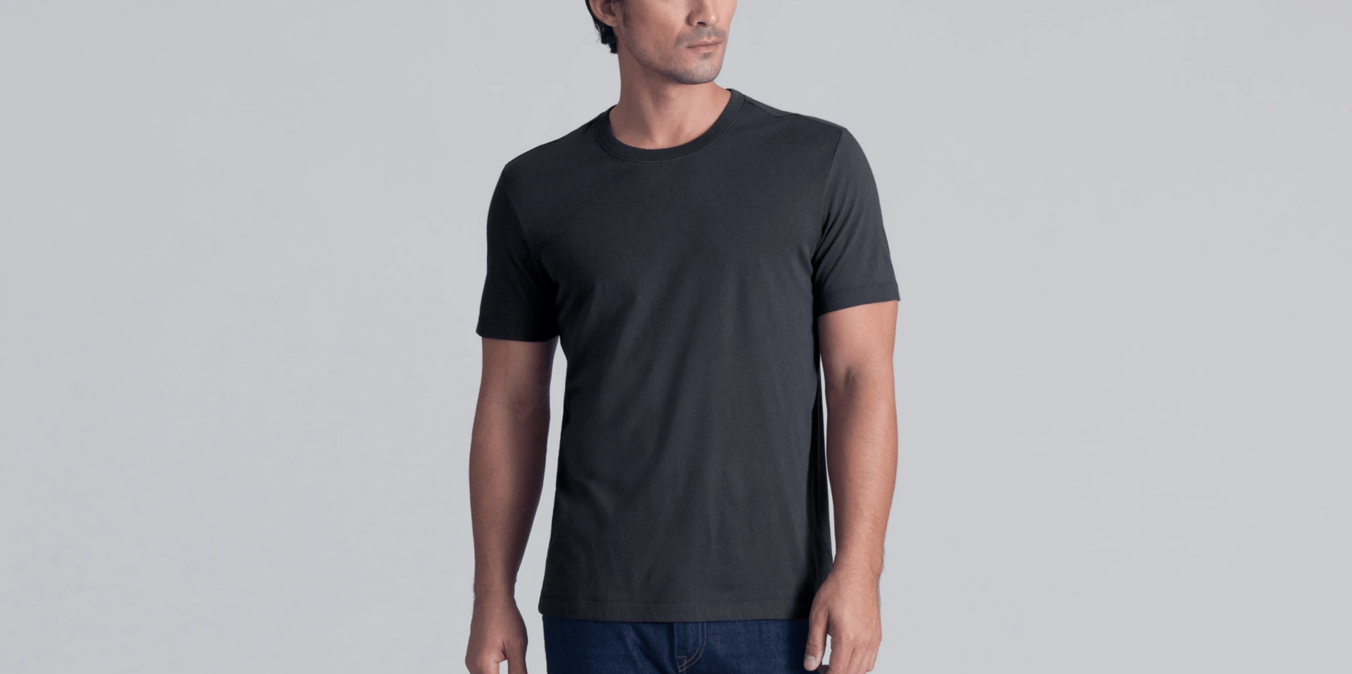 A model wearing a graphite tee shirt and jeans on a gray background.