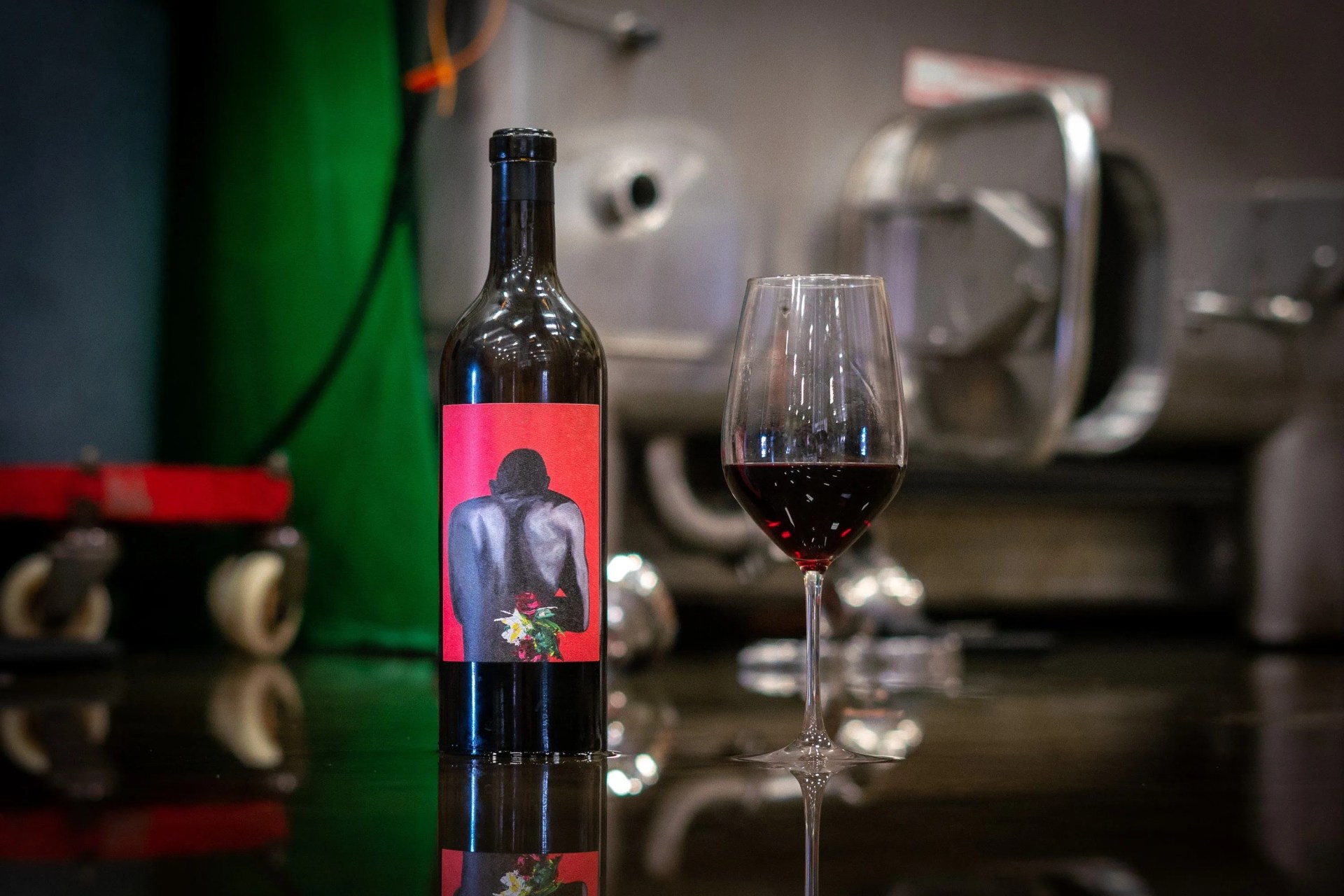 bottle of wine next to a half-filled wine glass with red wine