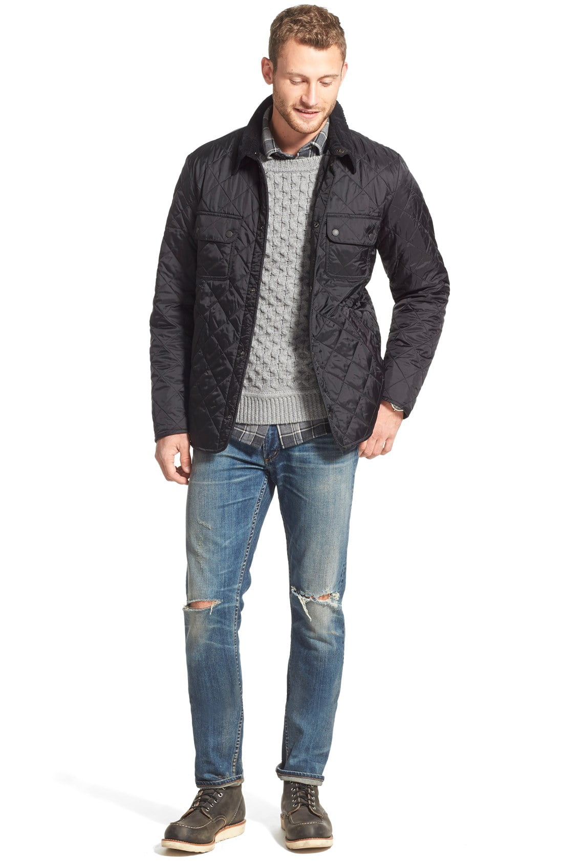 A model wearing a black quilted jacket, gray sweater and jeans on a gray background.