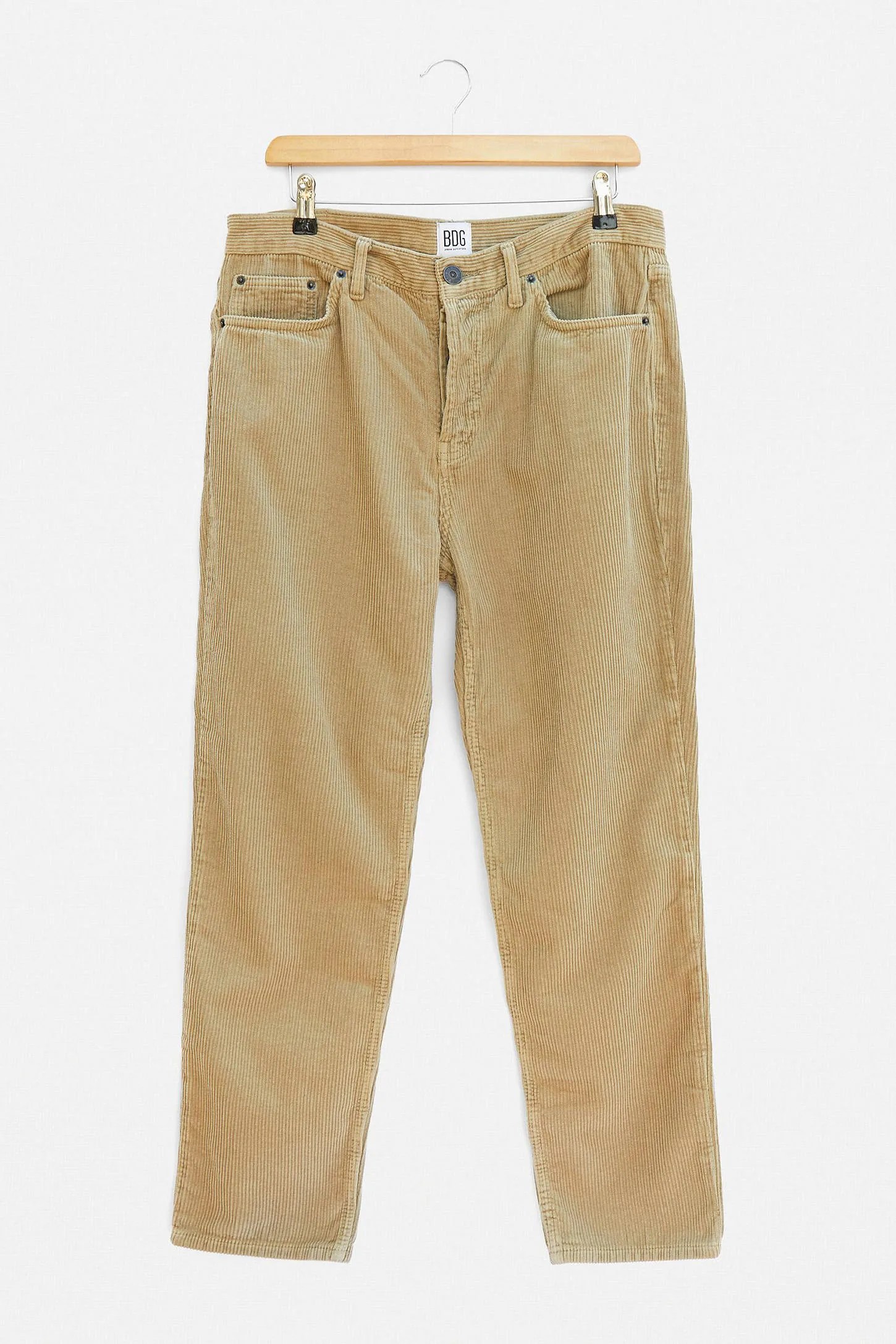 Cream corduroy pants on a hanger on a gray background.