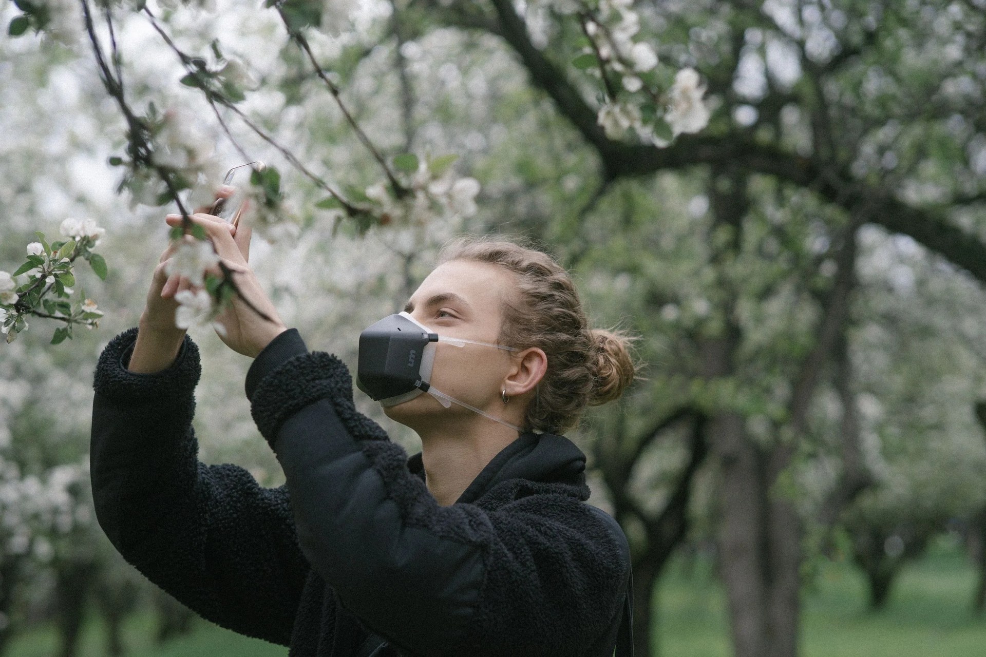 a person in a mask touching flowers on a tree