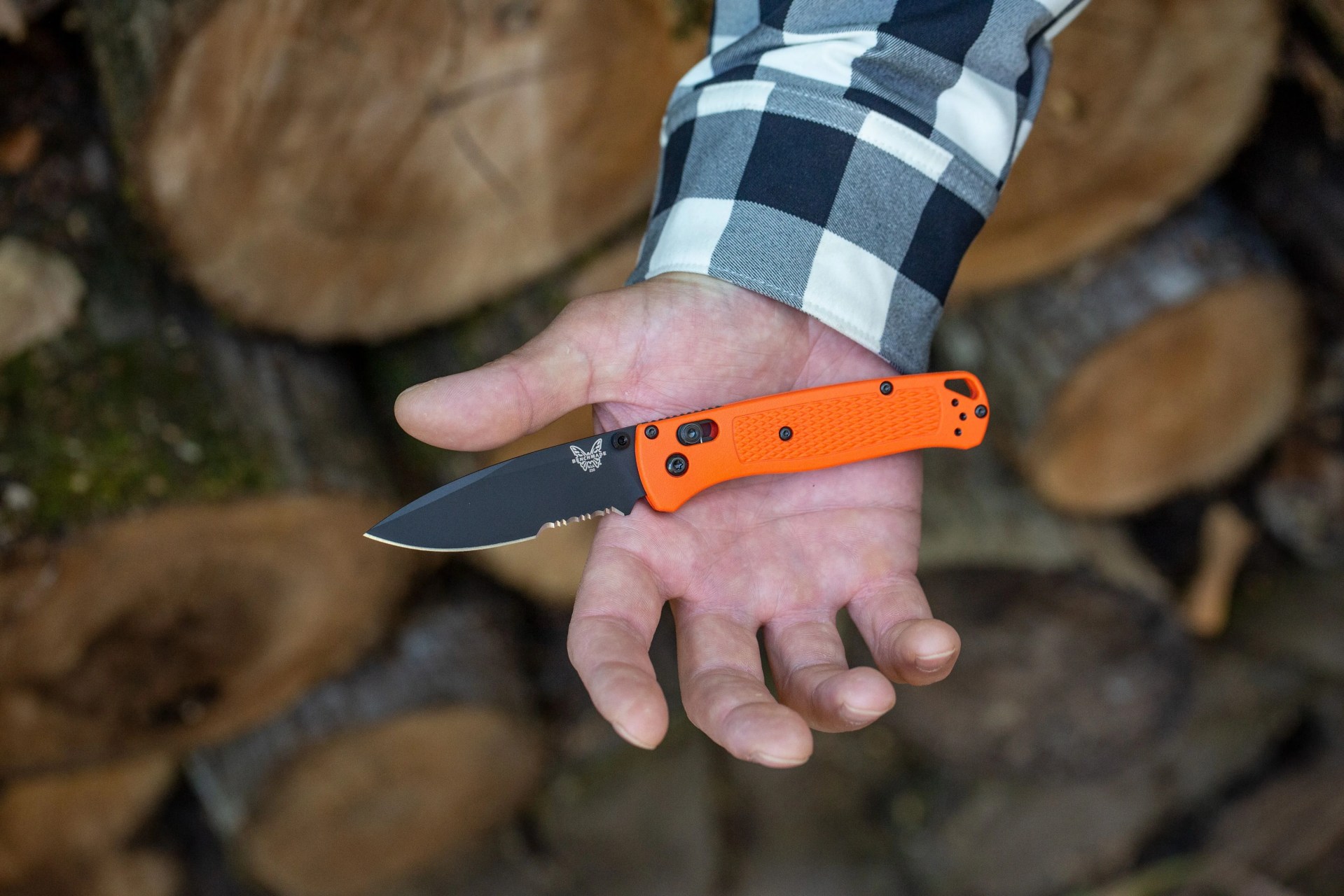 a hand holding a folding pocket knife with an orange handle and black blade