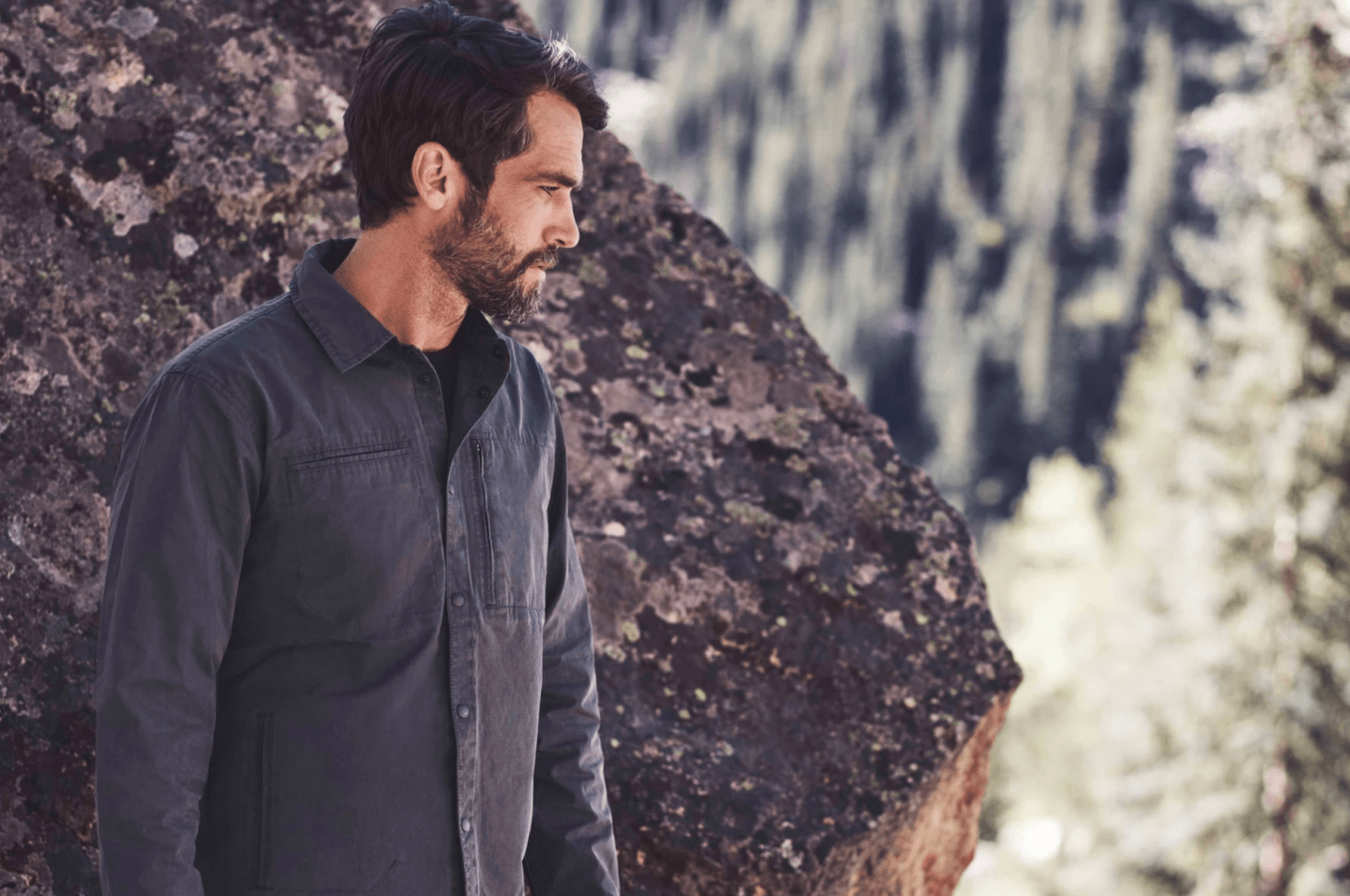 a model in front of a boulder wearing a graphite jacket