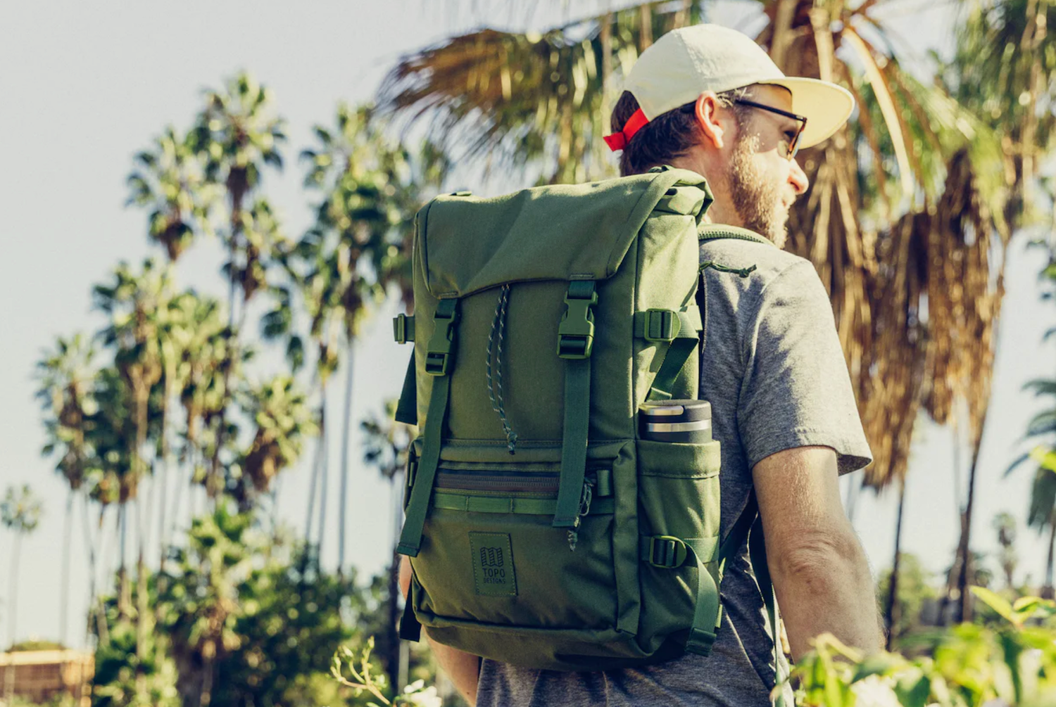 a model with an olive backpack in a jungle
