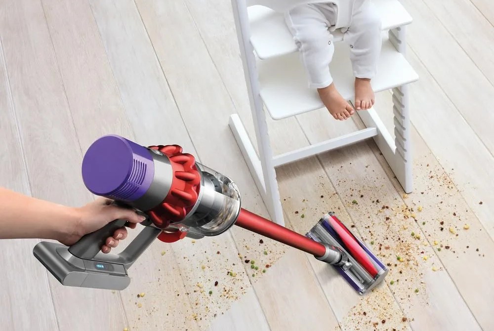 a vacuum cleaner cleaning up a mess underneath a baby in a high chair