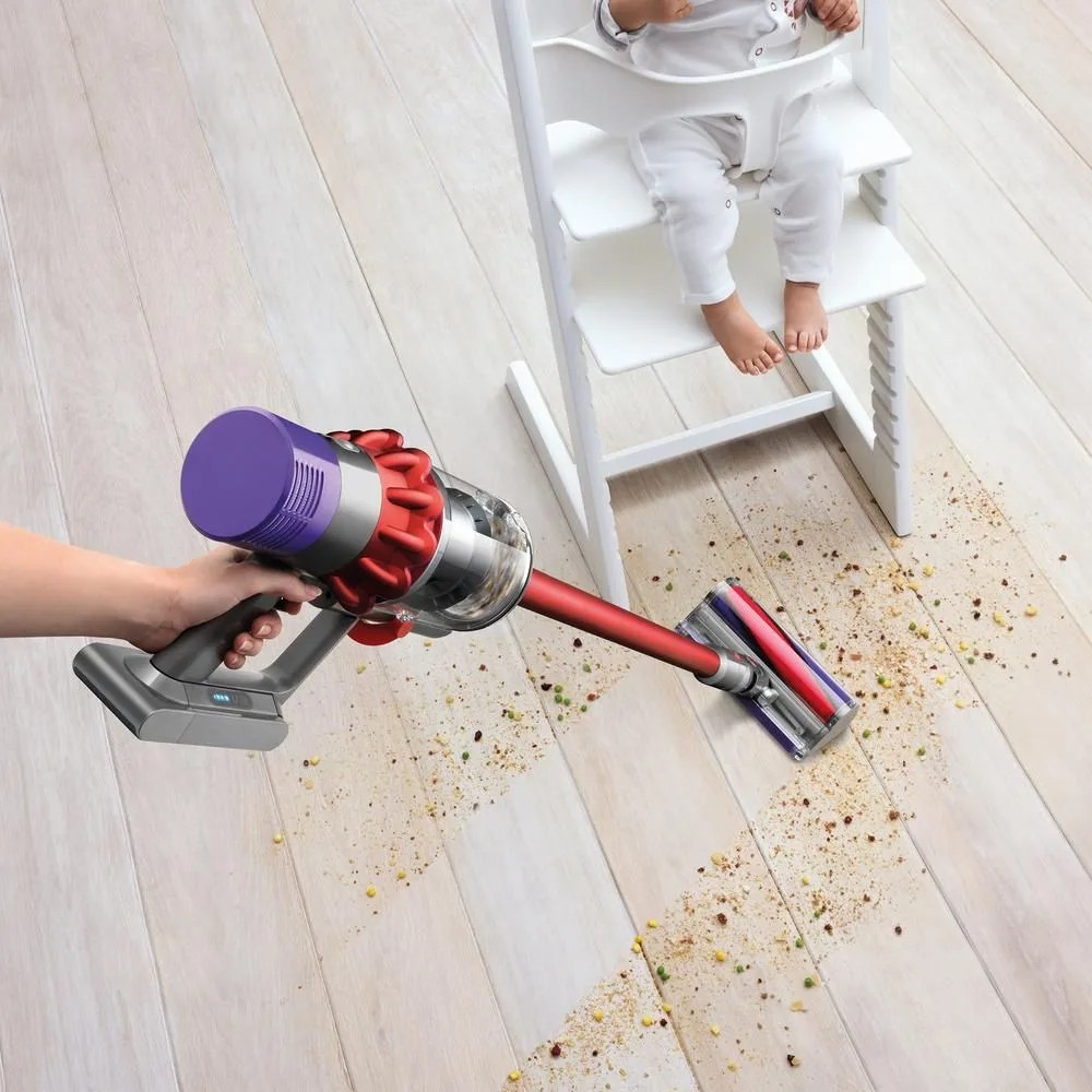 a vacuum cleaner cleaning up a mess underneath a baby in a high chair