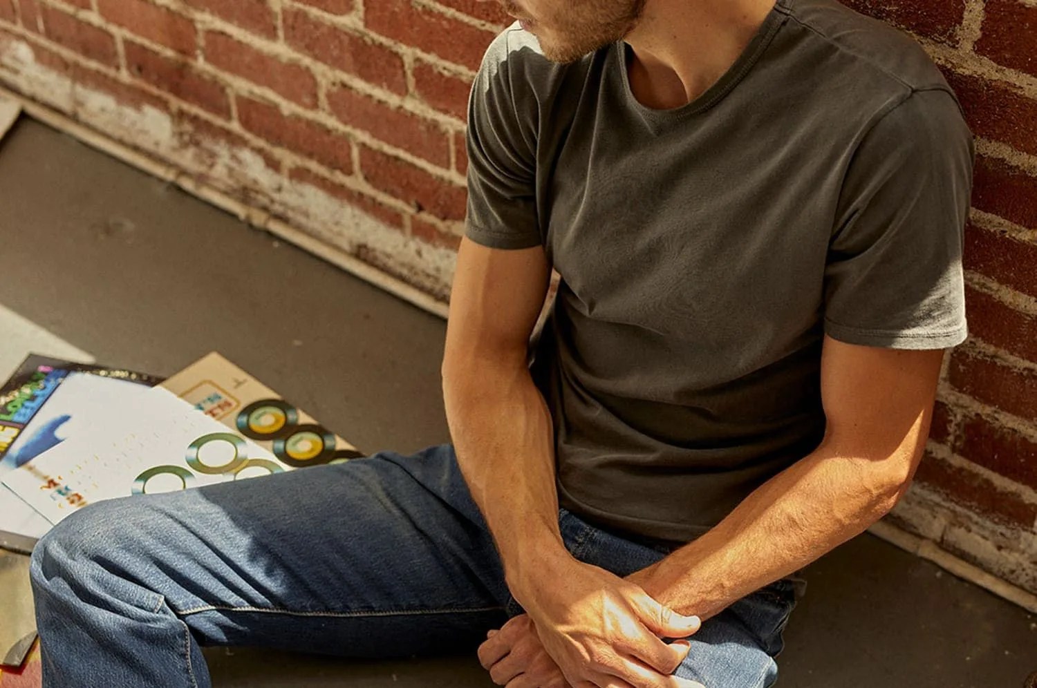 man sitting wearing jeans and green t shirt
