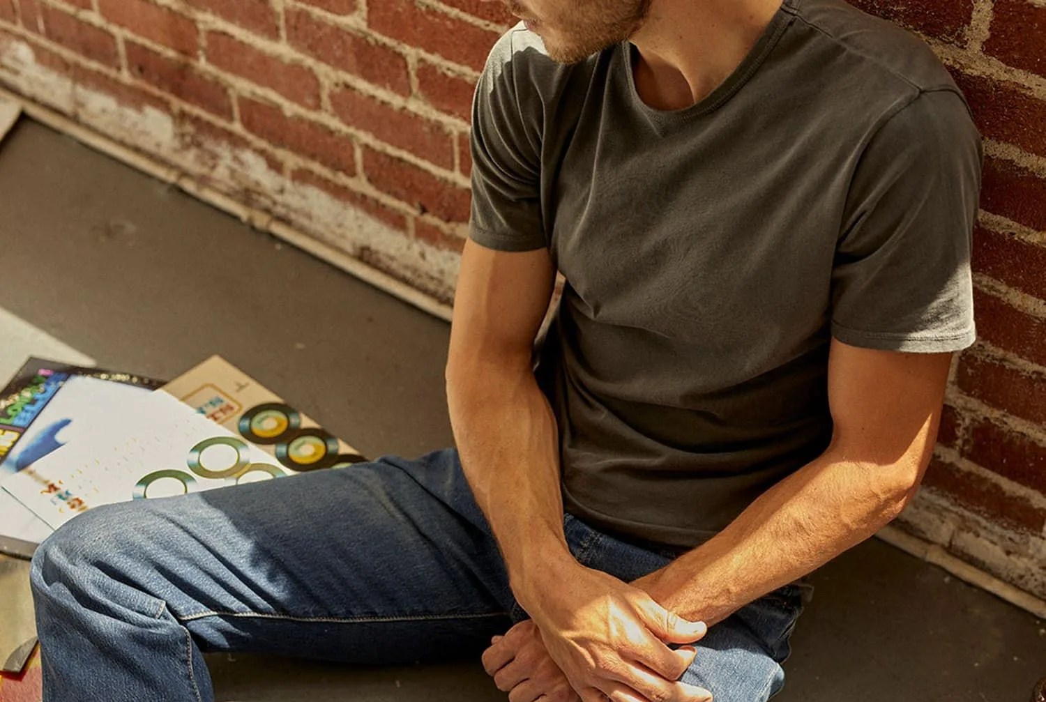 man sitting wearing jeans and green t shirt