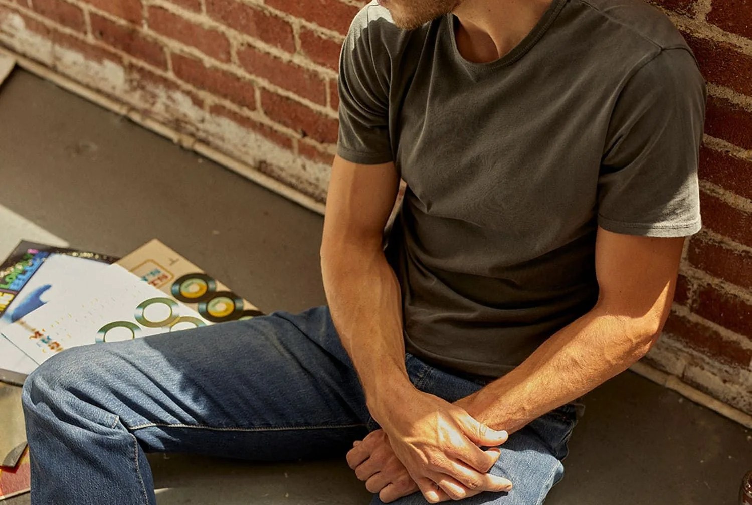 man sitting wearing jeans and green t shirt