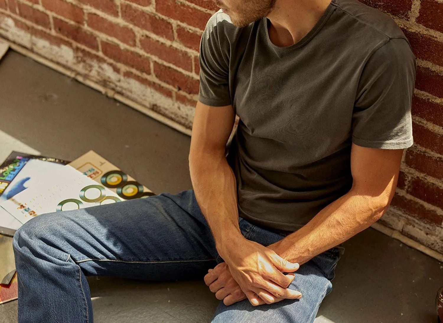 man sitting wearing jeans and green t shirt