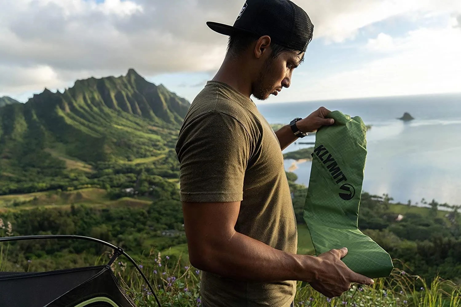 a man unfolding a green camping mattress