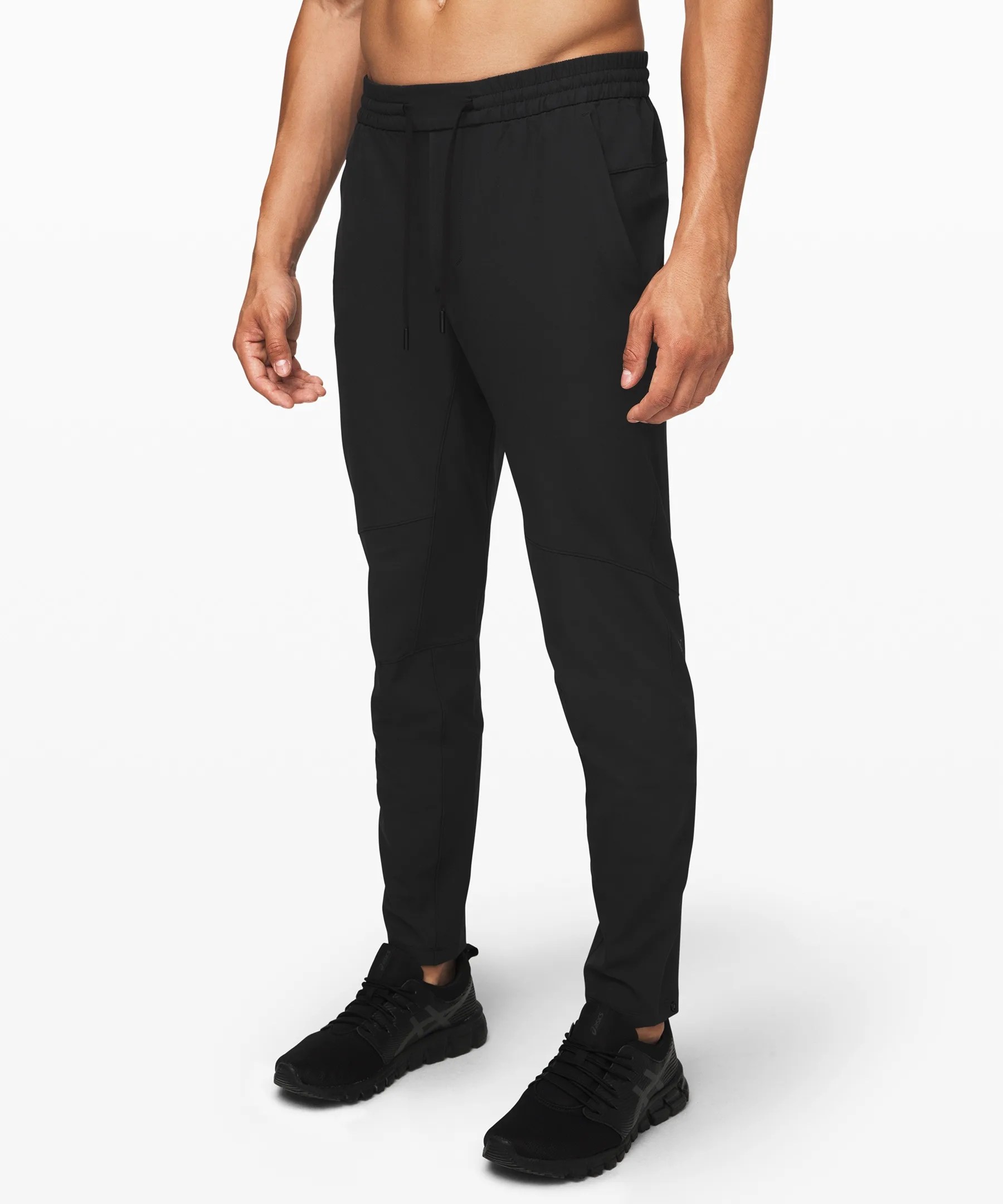 A model wearing black training pants and black sneakers