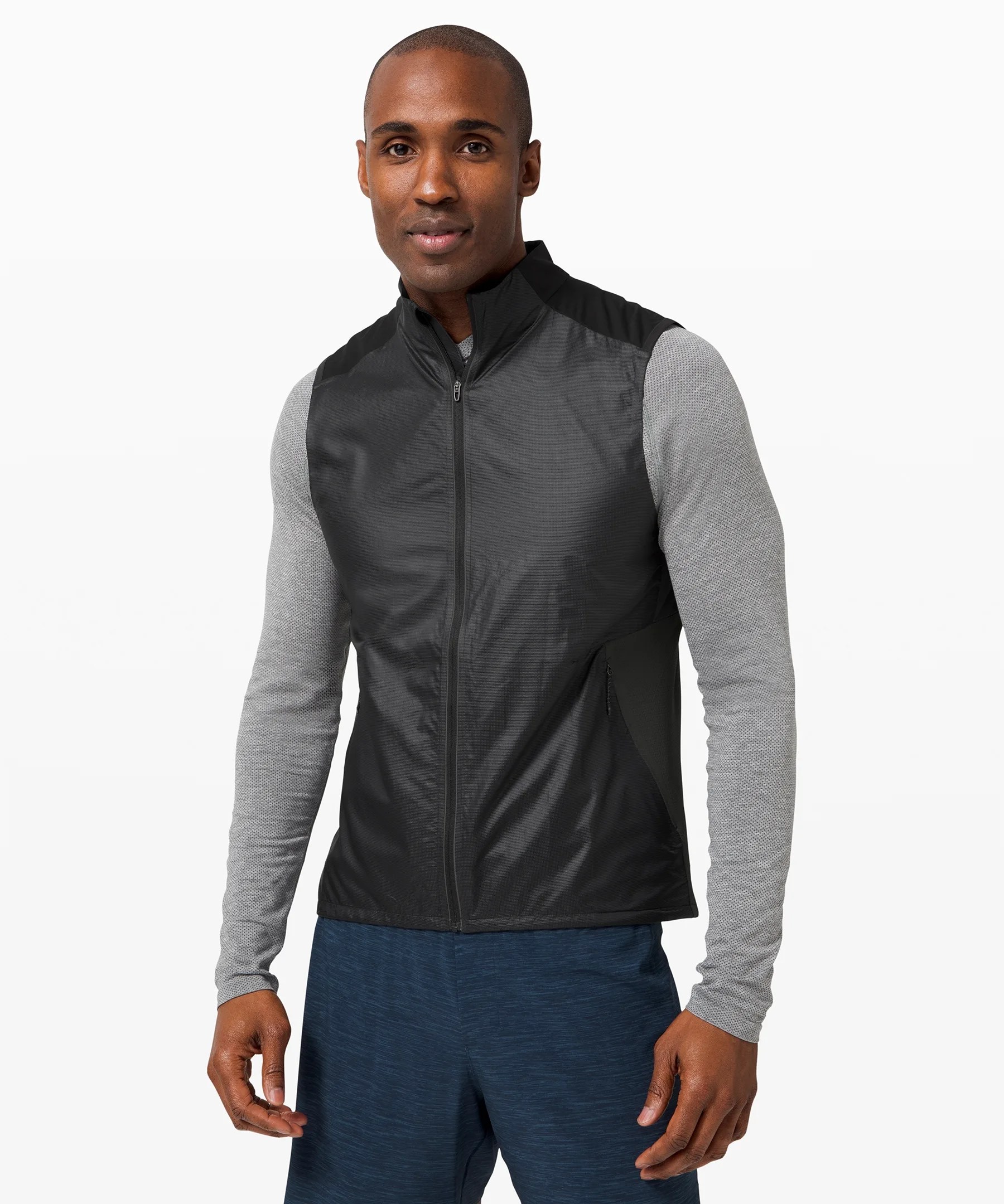 A model wearing a black vest and gray long sleeve shirt