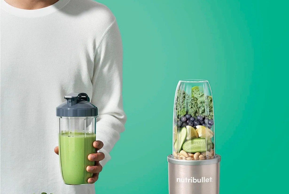 a male model blending up smoothies with fruits and vegetables