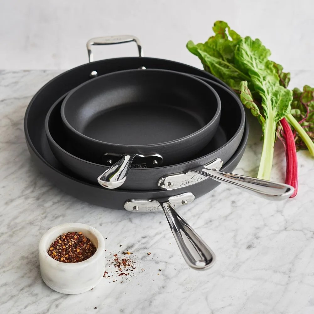 three skillets and some cooking ingredients
