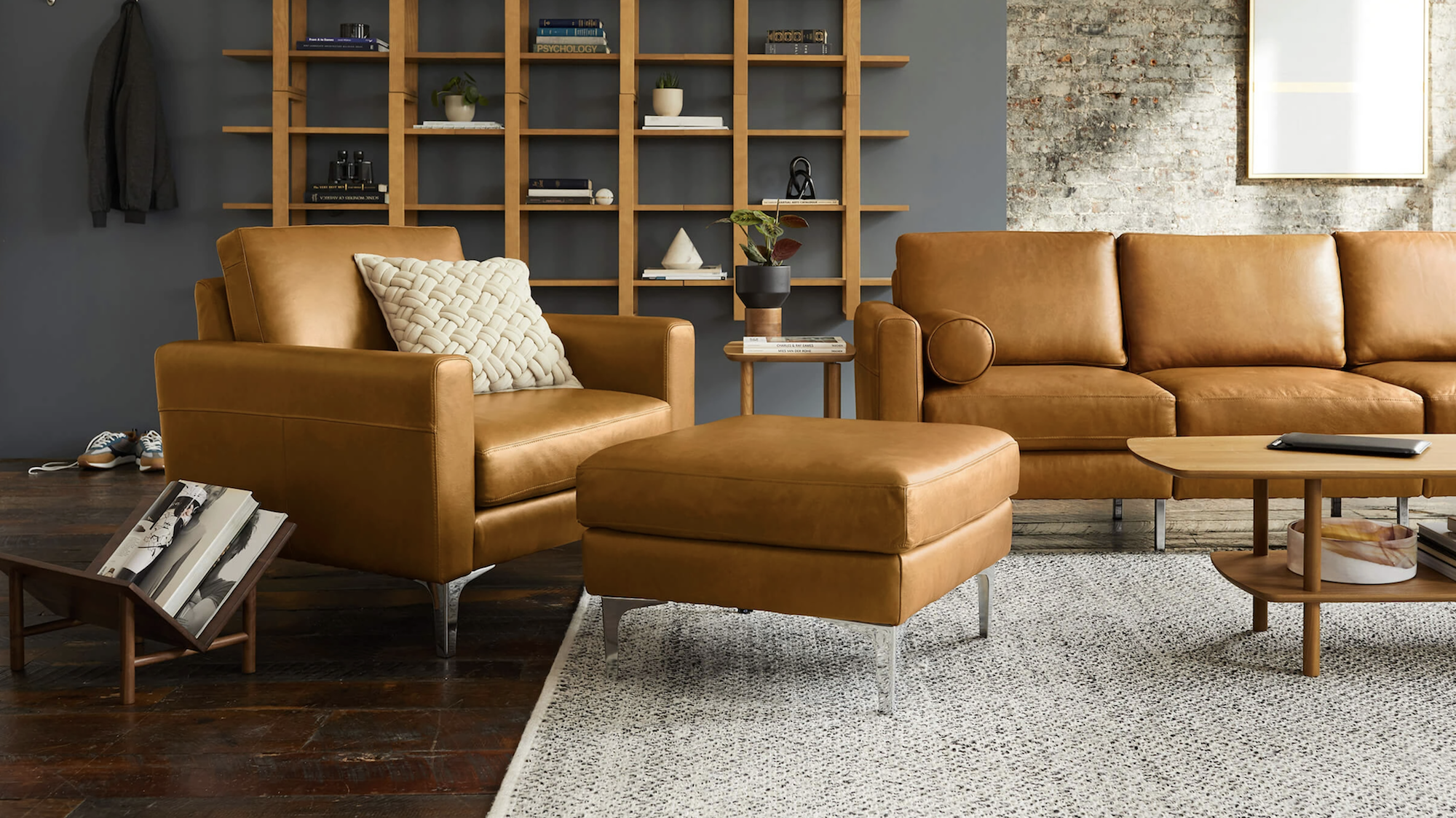 a living room scene with brown leather couch, chair and ottoman