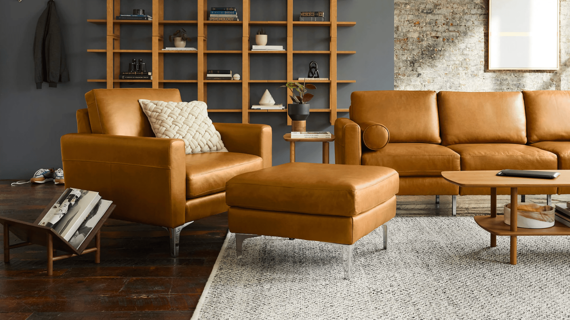 a living room scene with brown leather couch, chair and ottoman